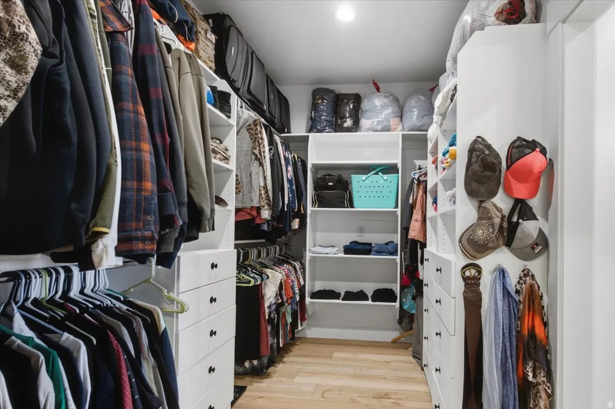 Walk-in closet with extensive built-in shelving, multiple hanging rods, integrated drawer storage, and light wood-finish flooring
