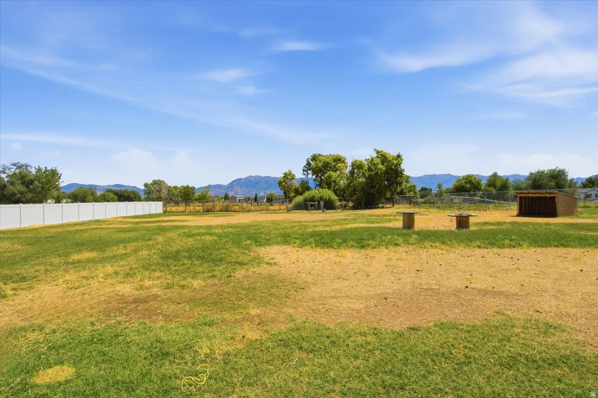Expansive open terrain featuring a white privacy fence and a small detached shed
