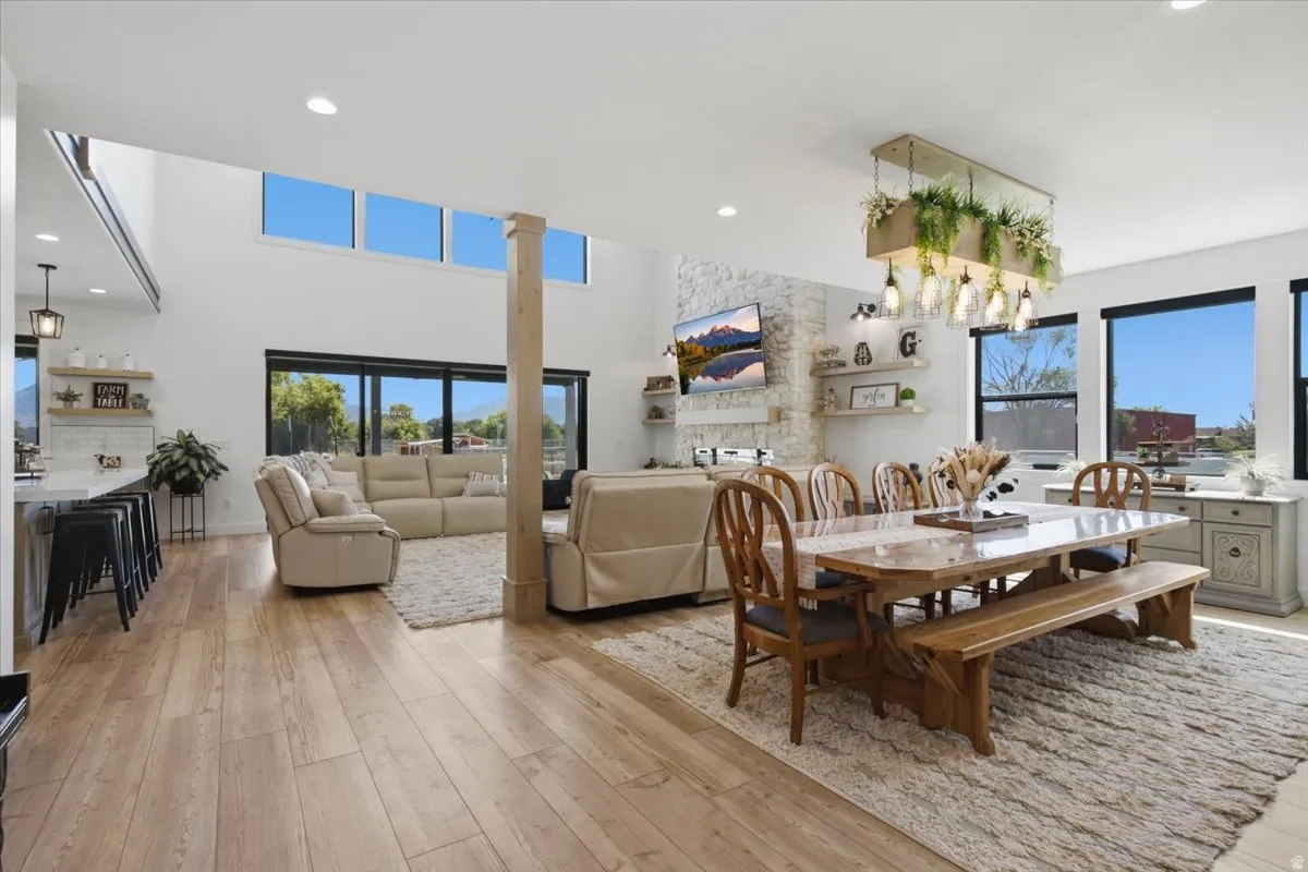 Expansive open-concept living area featuring wood-finish flooring, vaulted ceilings, and a decorative column