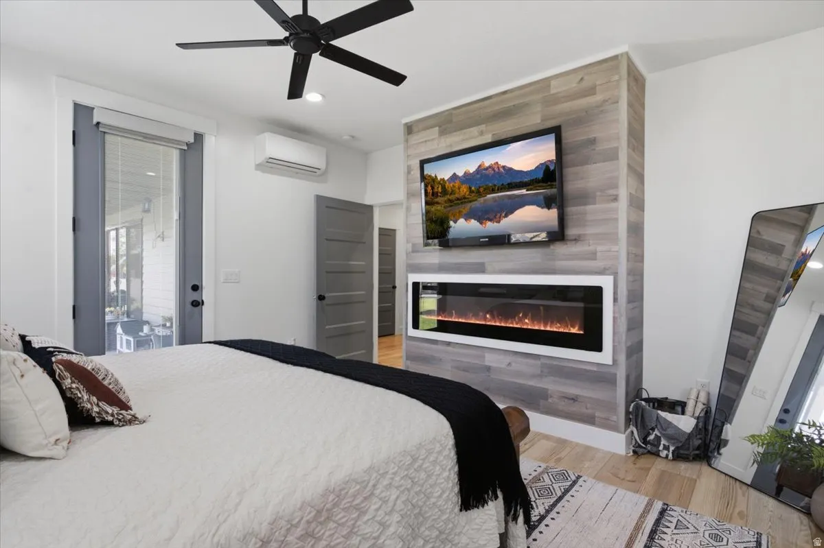 Wood-finish flooring, ceiling fan, built-in electric fireplace, wall-mounted television, and glass-paneled door to exterior