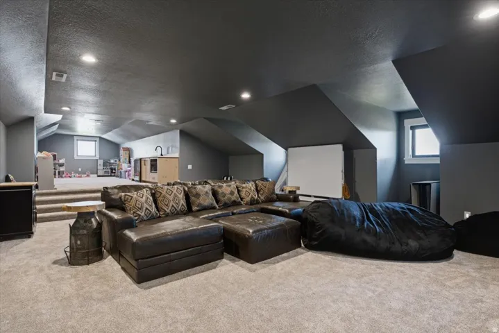 Carpeted recreation room featuring recessed lighting, a built-in projection screen, and a raised platform with additional space
