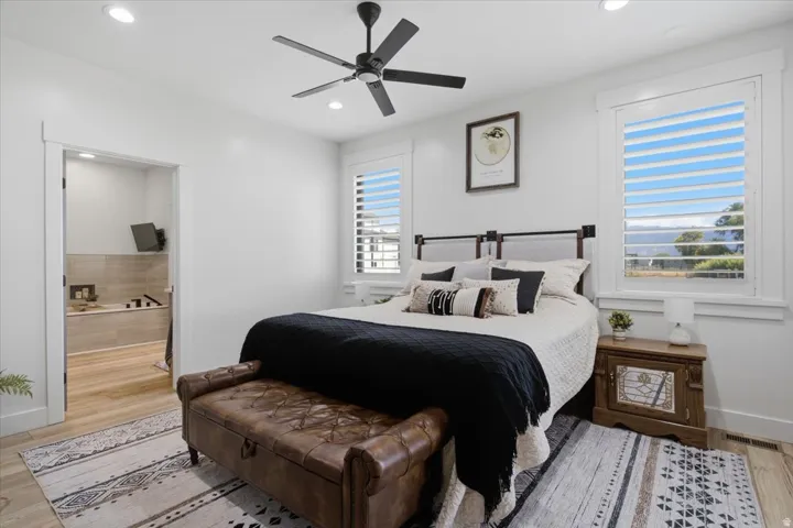 Recessed lighting, ceiling fan, wood-finish flooring, white plantation shutters, and an attached full bathroom