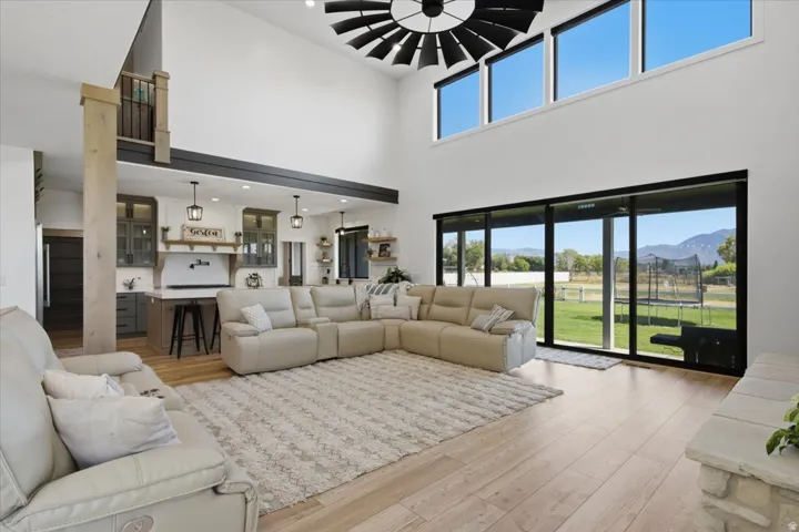 Vaulted ceiling with a large ceiling fan, wood-finish flooring, and expansive glass sliding doors