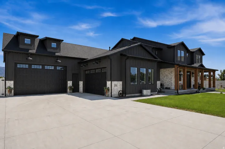 Modern farmhouse exterior with dark vertical siding, stone accents, and a covered porch