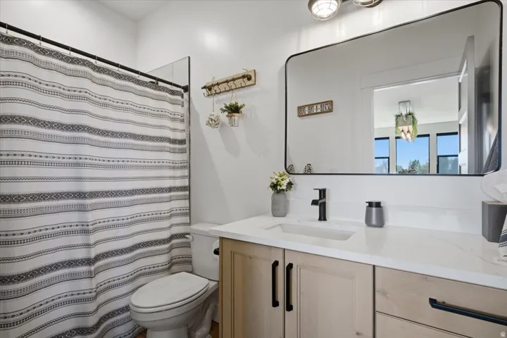 Vanity with wood-finish cabinetry, white countertop, rectangular sink, and matte black faucet