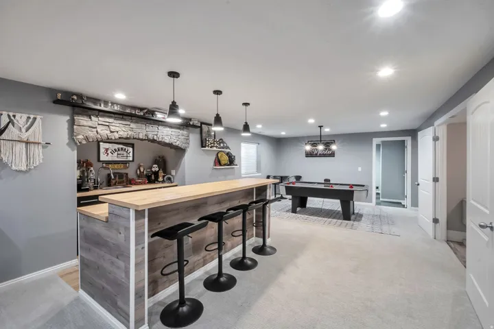 Built-in bar with stone archway accent, wood-finish paneling, and pendant lighting