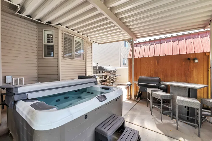 Private patio featuring a hot tub, concrete flooring, and an overhead awning