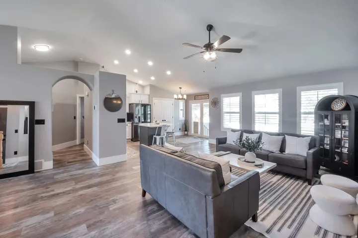 Vaulted ceilings with recessed lighting, wood-finish flooring, arched doorway, and plantation shutters