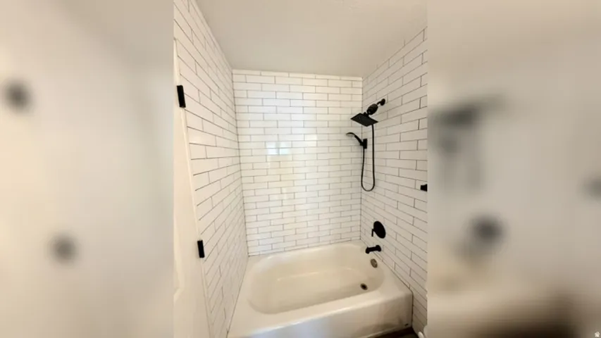 Bathtub with white subway tile surround, matte black showerhead, and coordinating bath fixtures