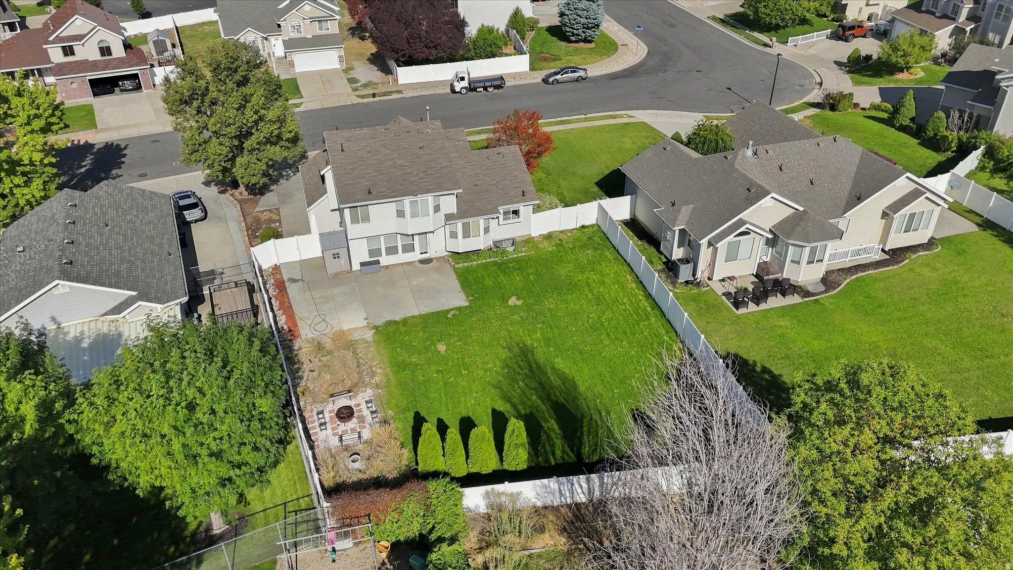 Expansive backyard featuring a manicured lawn, concrete patio, and a dedicated fire pit area
