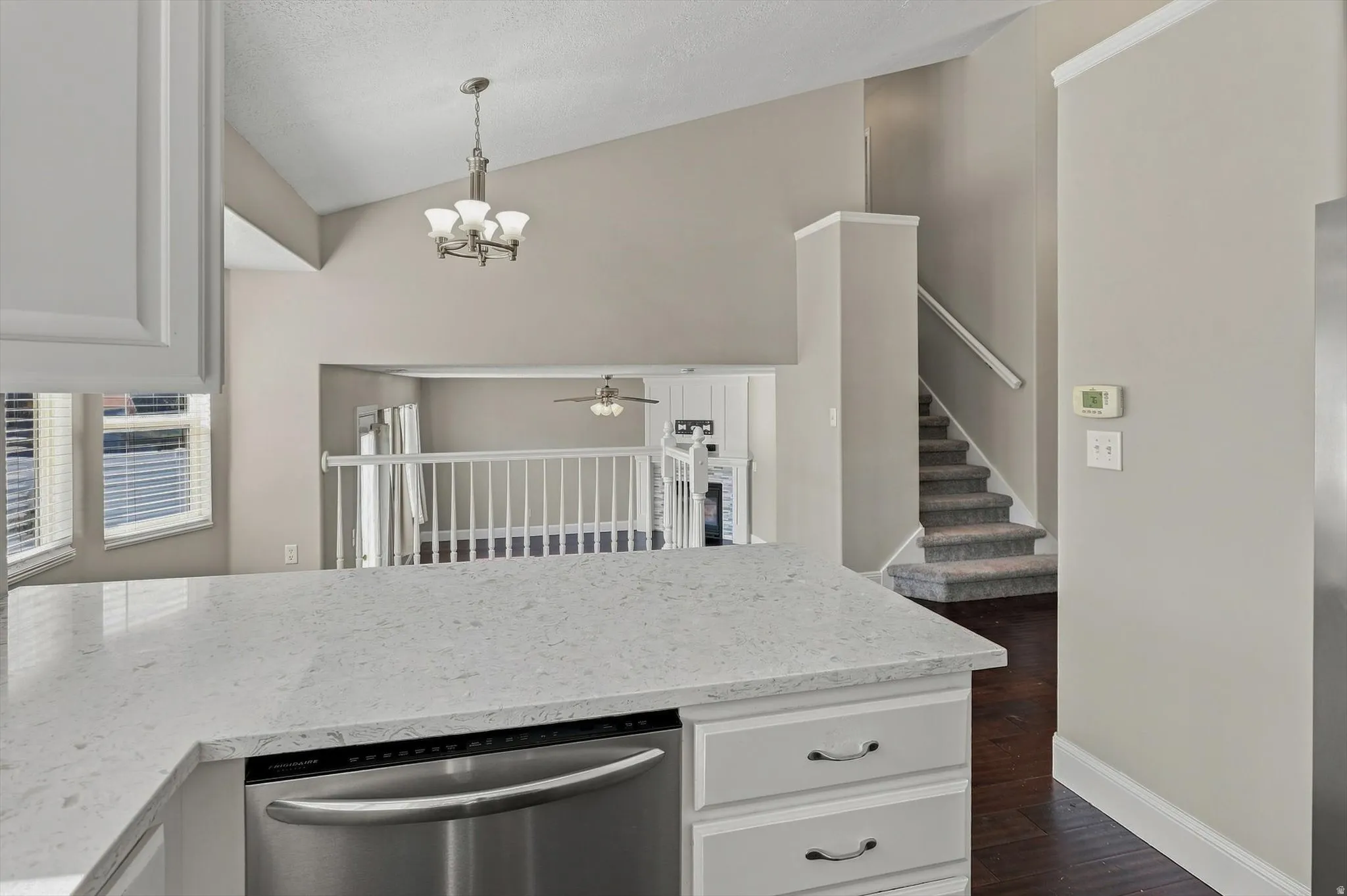 Kitchen island with a light-toned countertop, stainless steel dishwasher, and white cabinetry