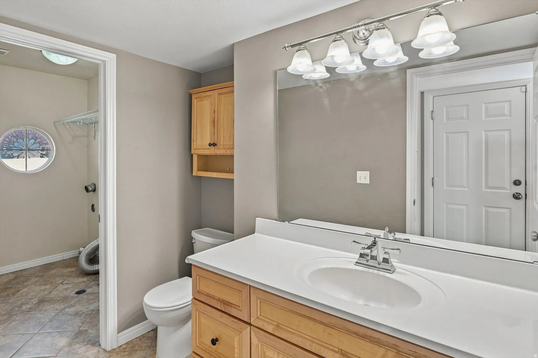 Bathroom featuring a wood-finish vanity with an integrated sink, a large mirror, and a five-light fixture