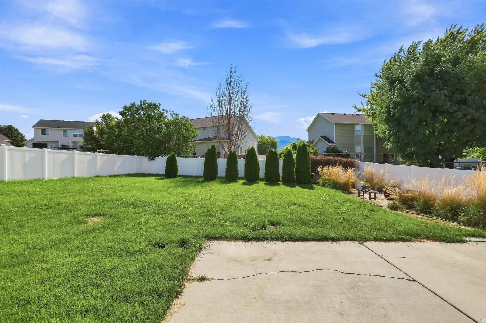 Expansive green lawn with a white privacy fence