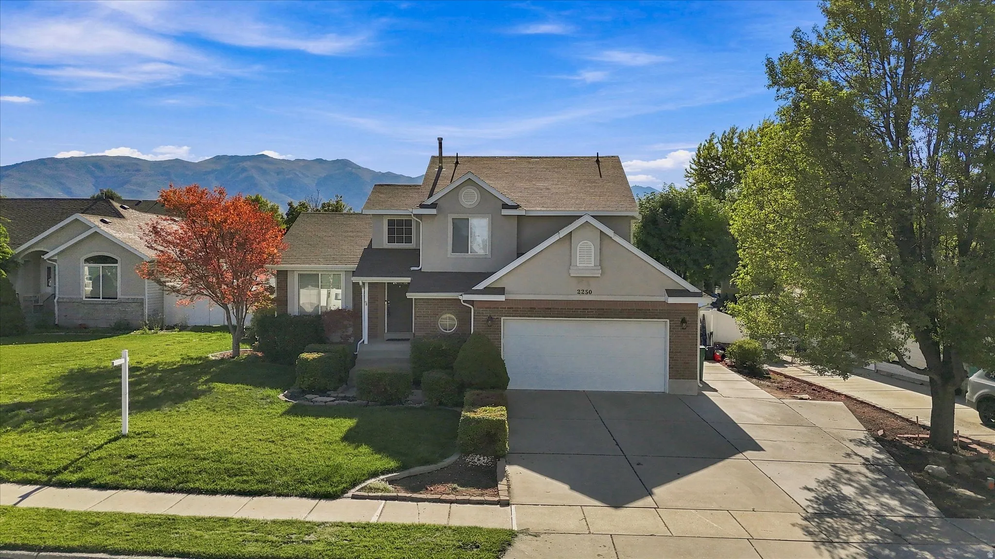 Two-story residence featuring a two-car garage, concrete driveway, and front lawn