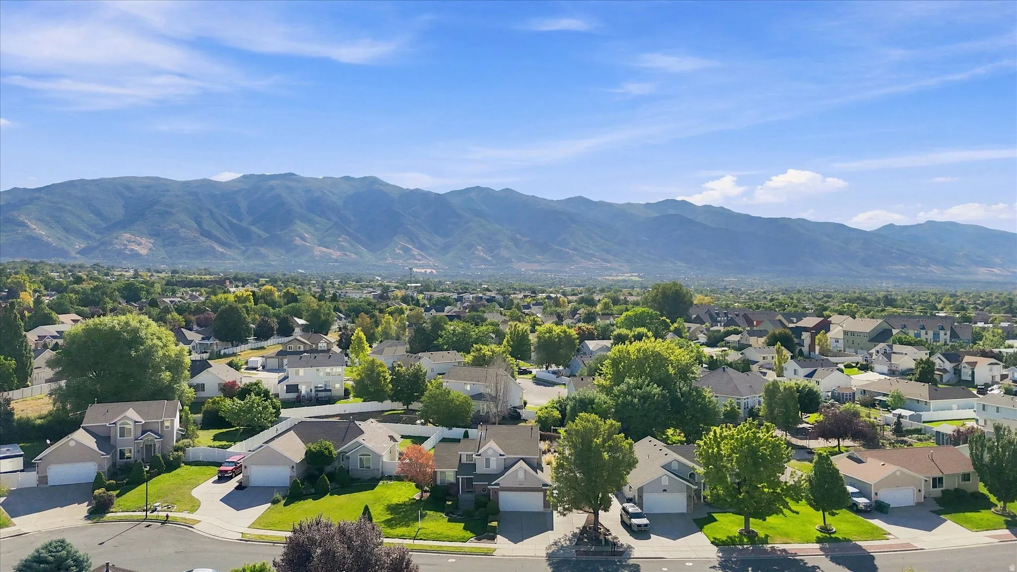 Mountain backdrop, residential street, detached homes, mature trees, clear blue sky