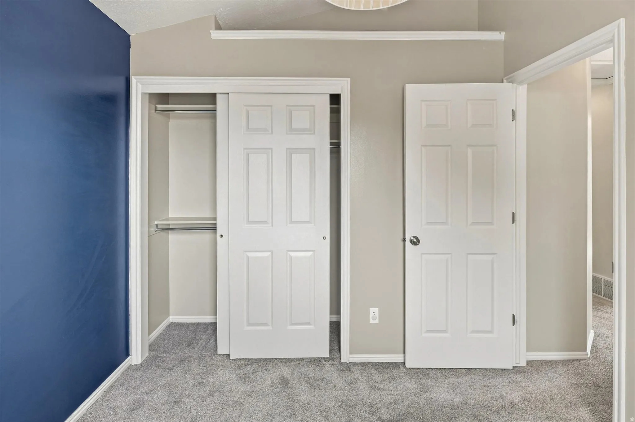 Built-in closet with sliding panel doors, six-panel interior doors, and neutral grey carpeting
