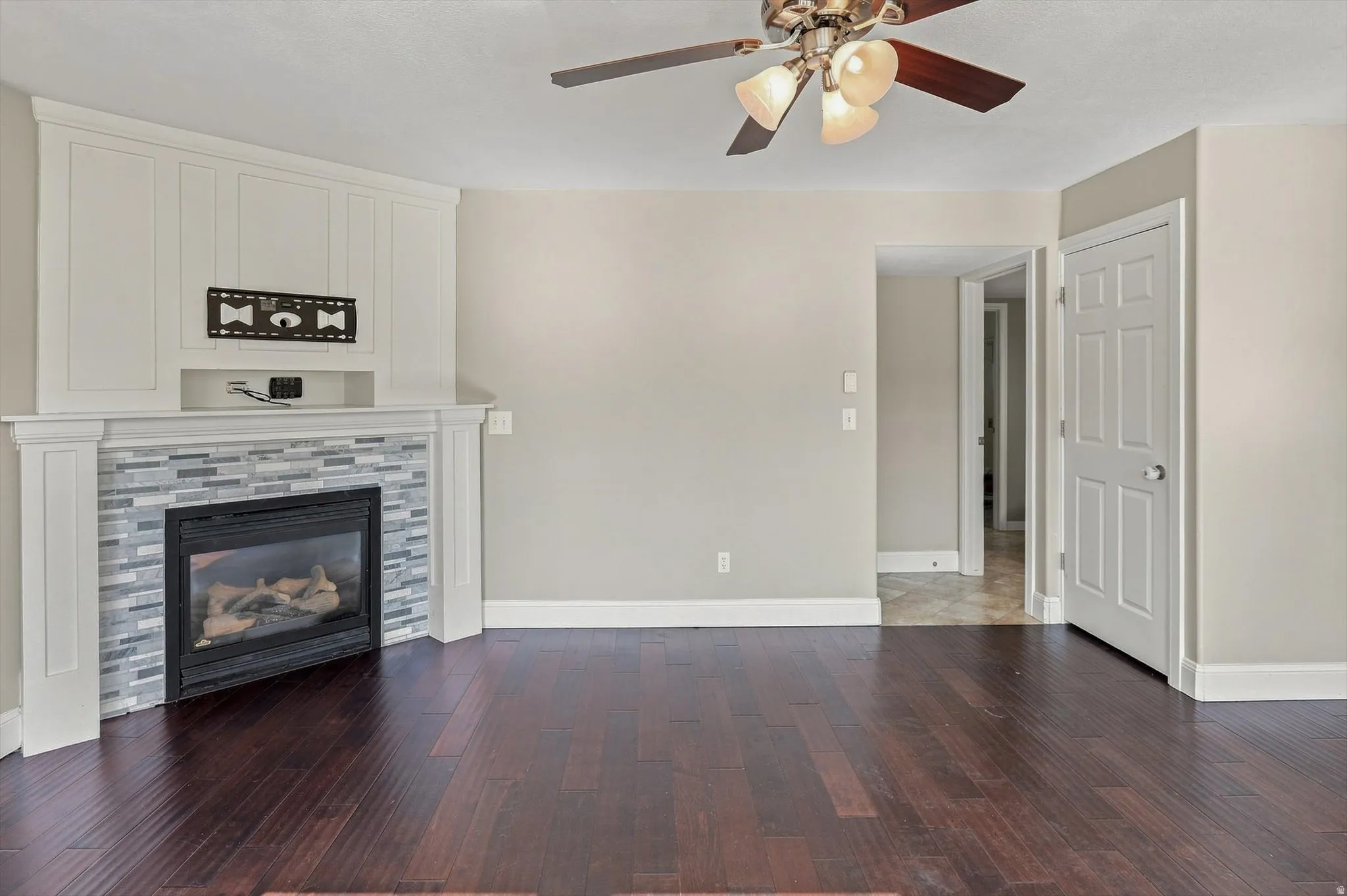Corner fireplace with a tile surround, built-in cabinetry, and a dark wood-finish flooring