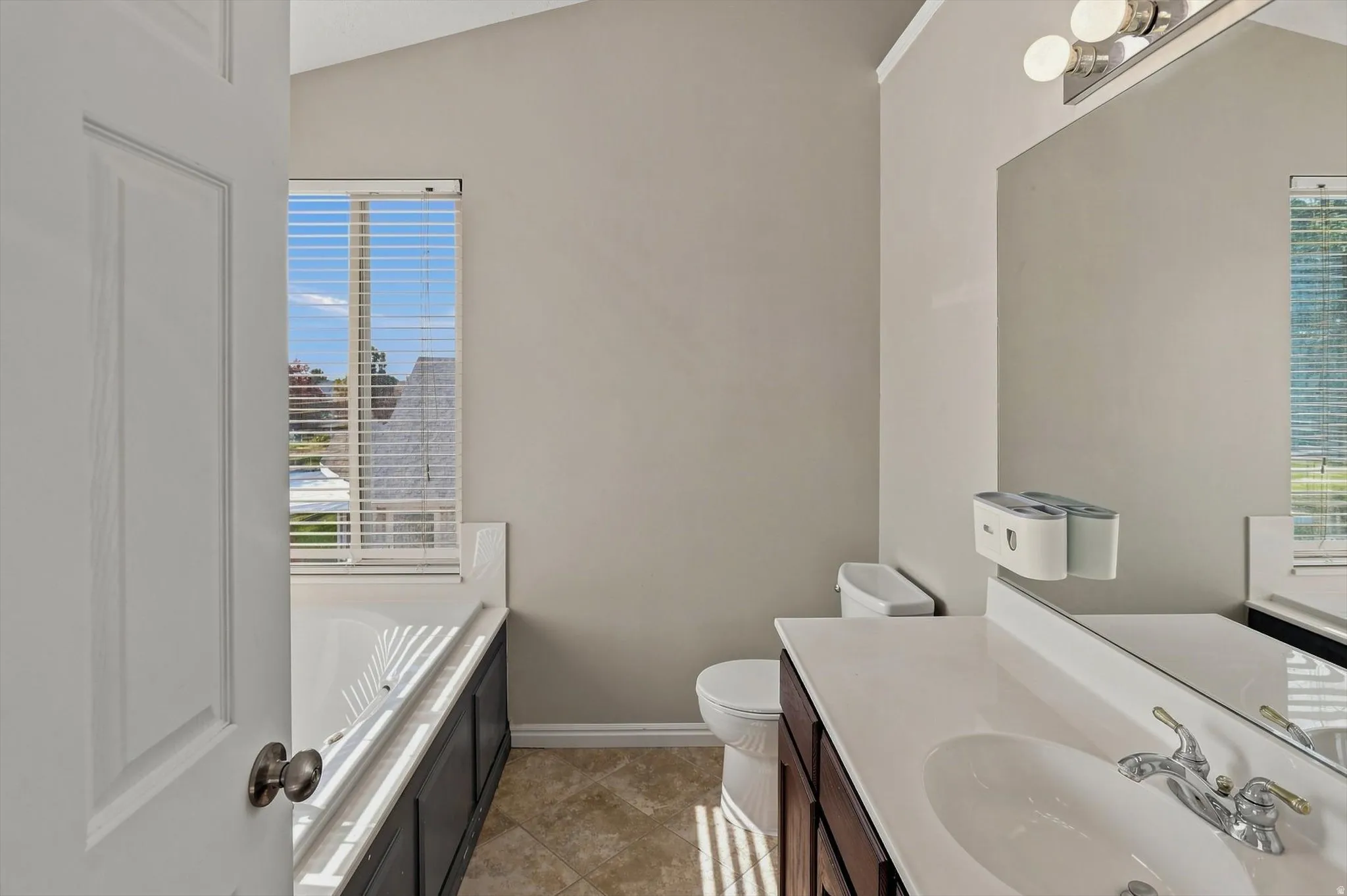 Bright bathroom featuring dual vanities with chrome fixtures, ceramic vessel sinks, and ample counter space