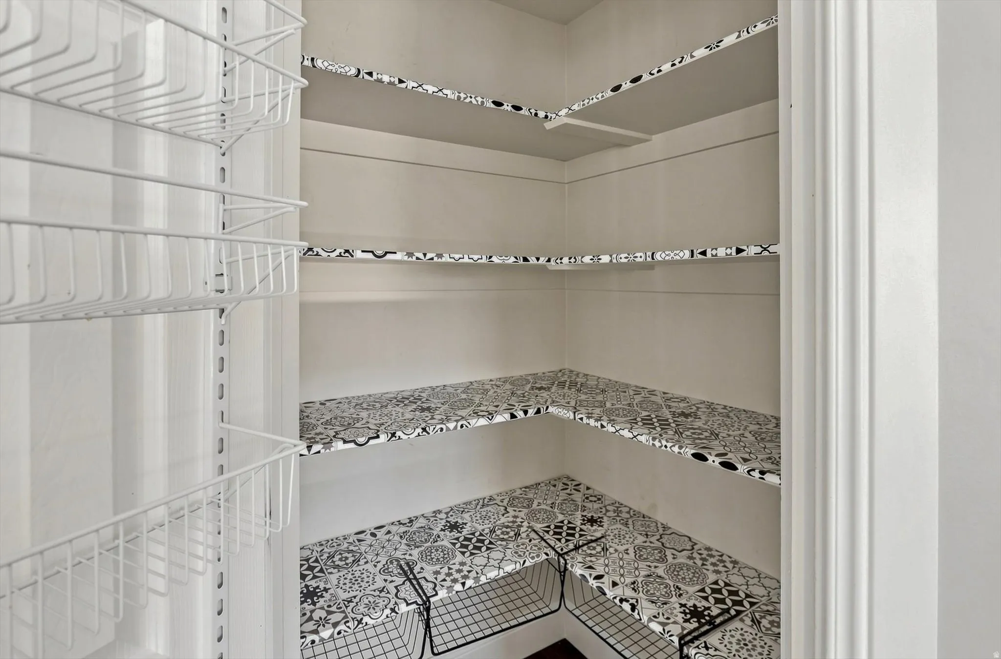 Custom pantry with patterned shelf liners, multiple wire basket organizers, and built-in shelving