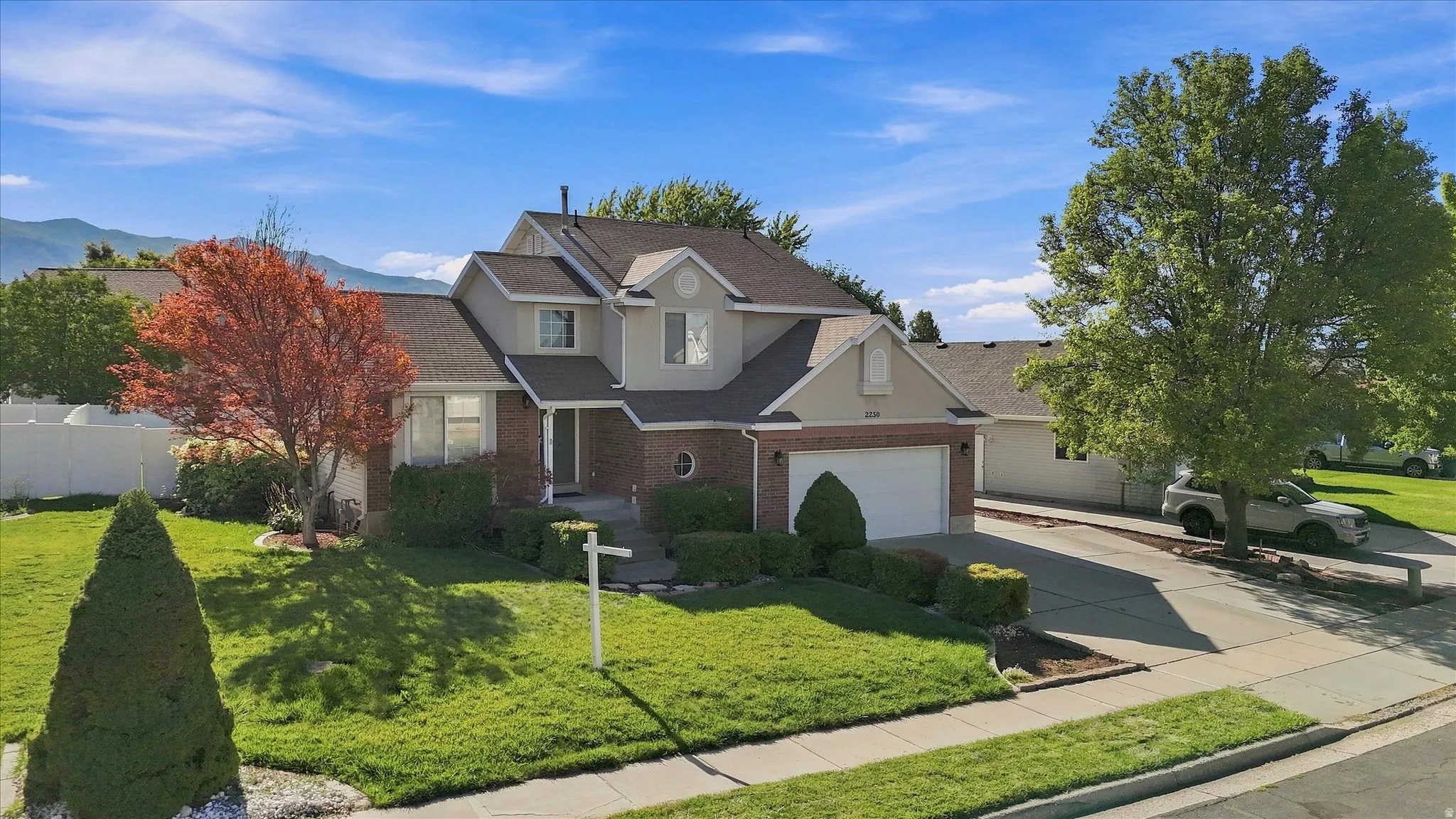 Two-story residence with a brick and stucco exterior, attached garage, and a concrete driveway