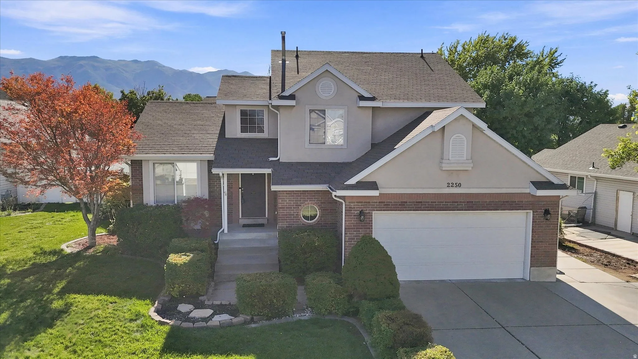 Two-story residence featuring brick and stucco exterior, an attached two-car garage, and a concrete driveway