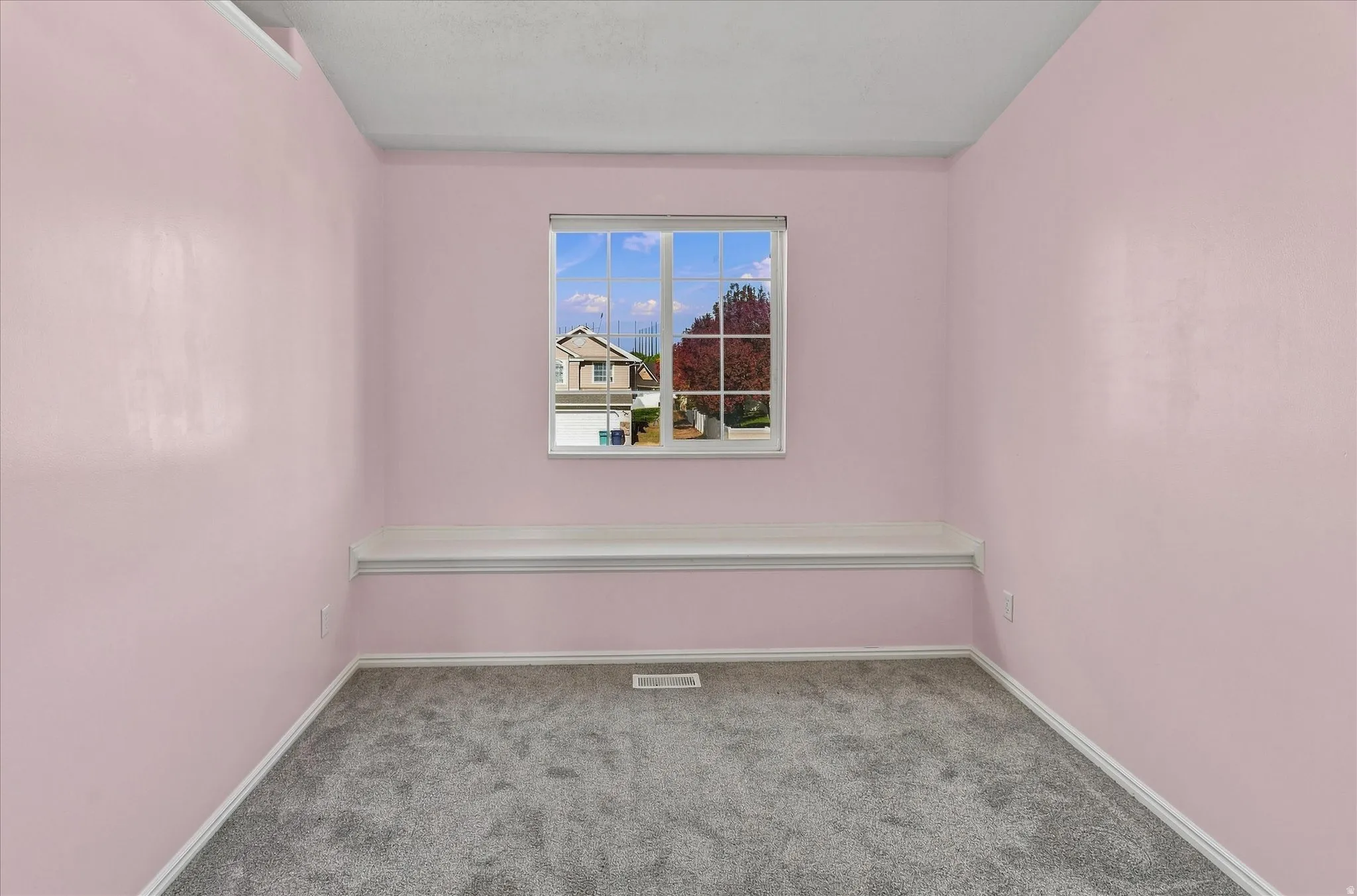 Built-in window bench, double-pane window, and grey carpet flooring