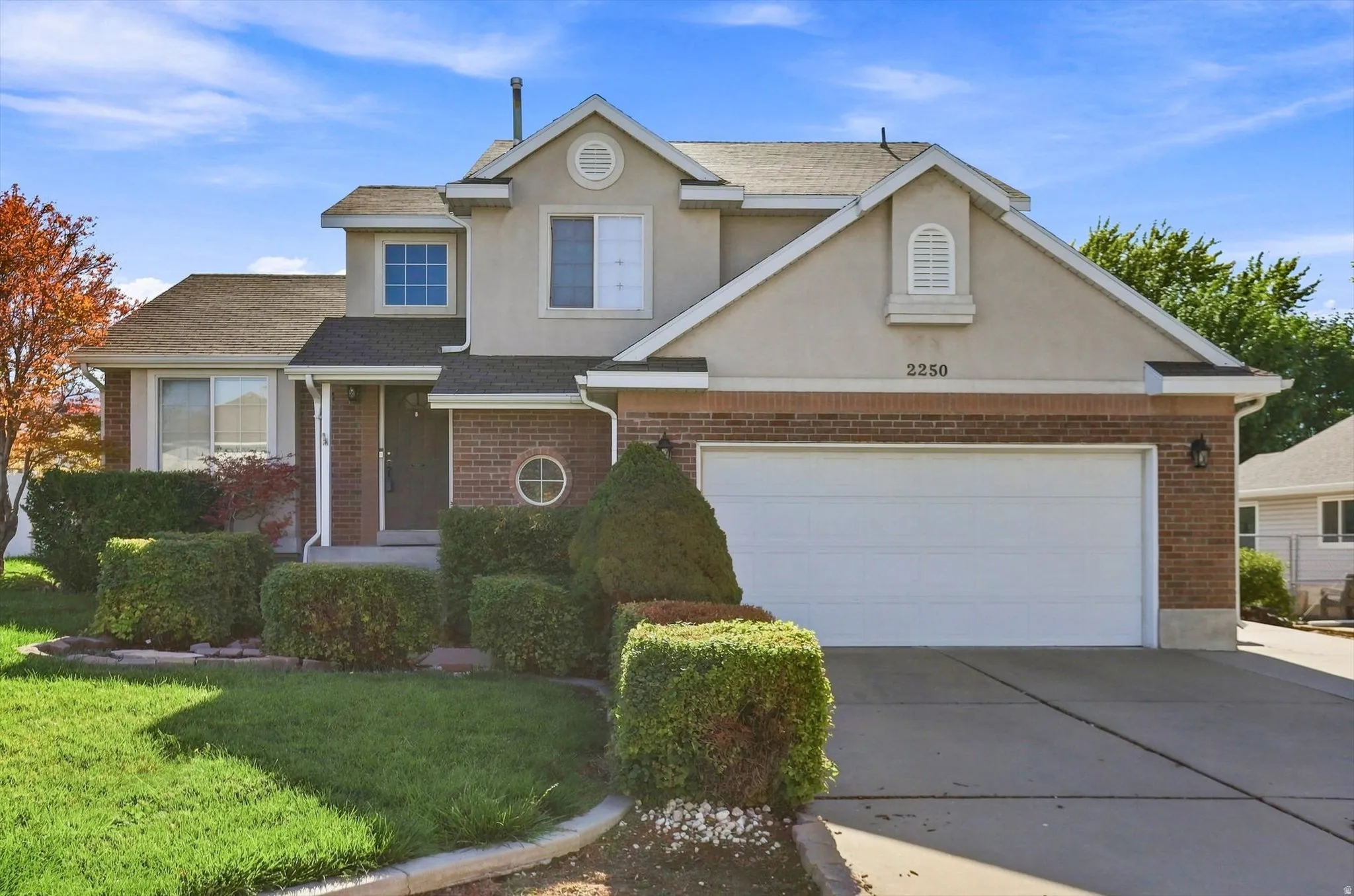 Two-story residence featuring a brick and stucco exterior, an attached two-car garage, and a concrete driveway
