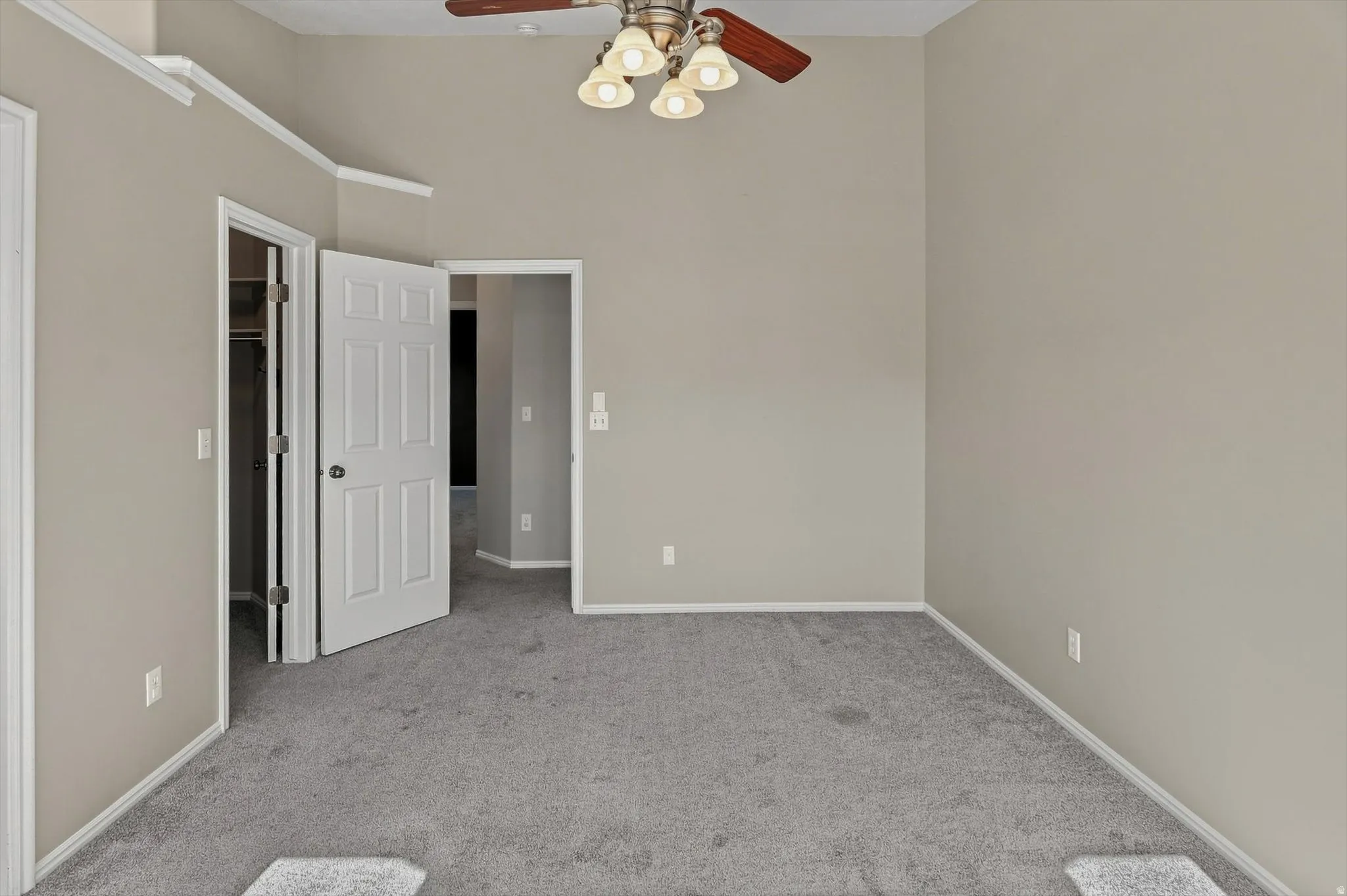 Neutral wall paint, ceiling fan with light fixture, carpeted flooring, white trim, and interior doors