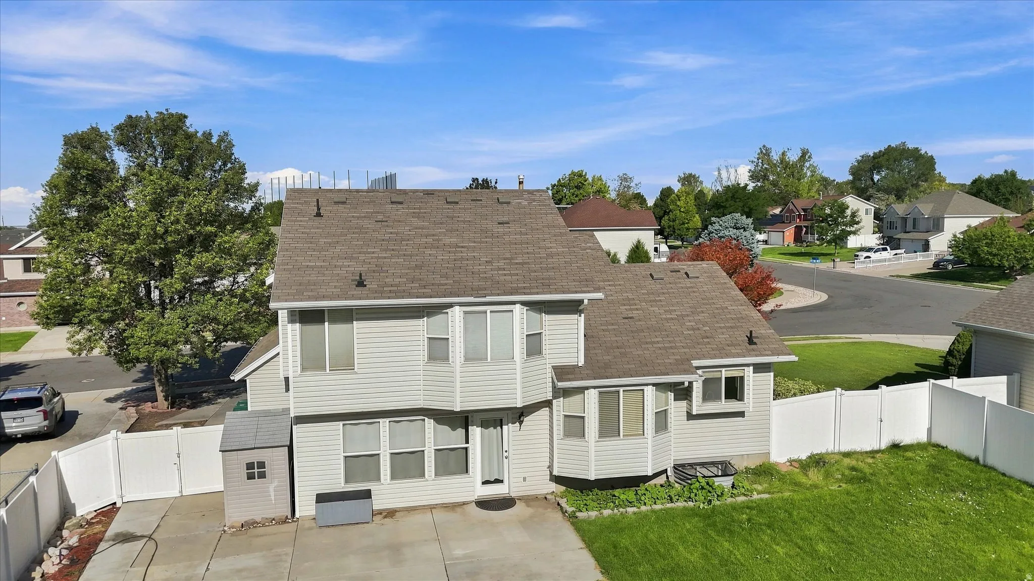 Two-story residence with light-colored siding, a brown shingle roof, and multiple bay windows