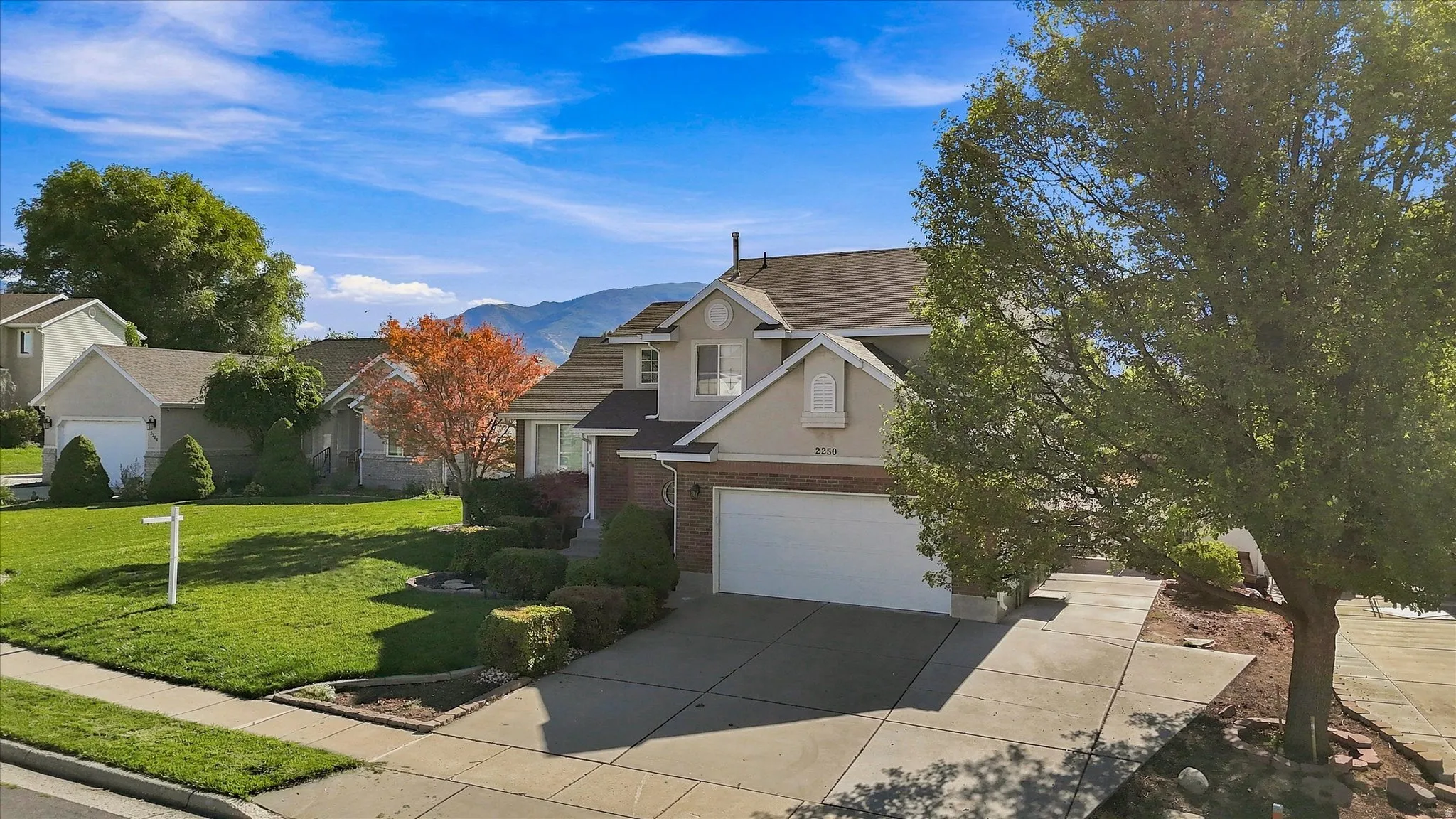 Two-story residence featuring a two-car garage, concrete driveway, and established landscaping