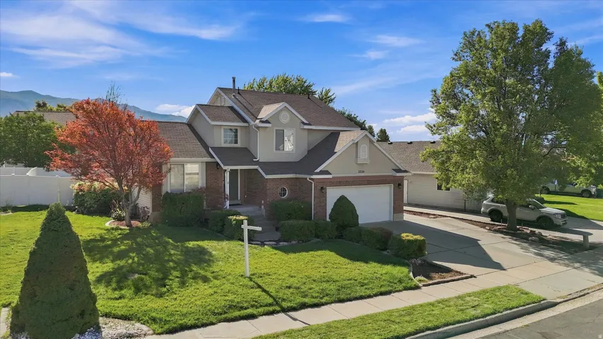 Two-story residence with a brick and stucco exterior, attached garage, and a concrete driveway