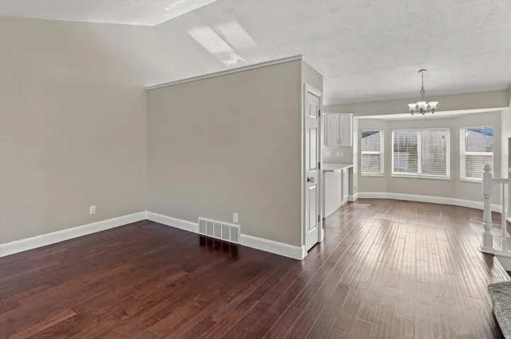 Hardwood flooring, painted interior walls, white trim, bay windows, and a built-in chandelier
