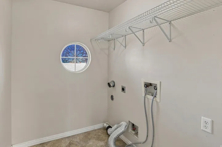 Laundry area featuring tile flooring, a circular stained-glass window, and overhead wire shelving