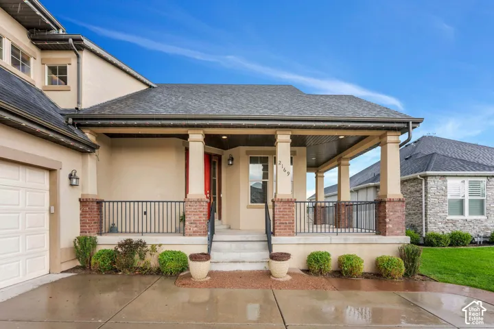 Inviting covered front porch with brick column bases, metal railing, and a red entry door