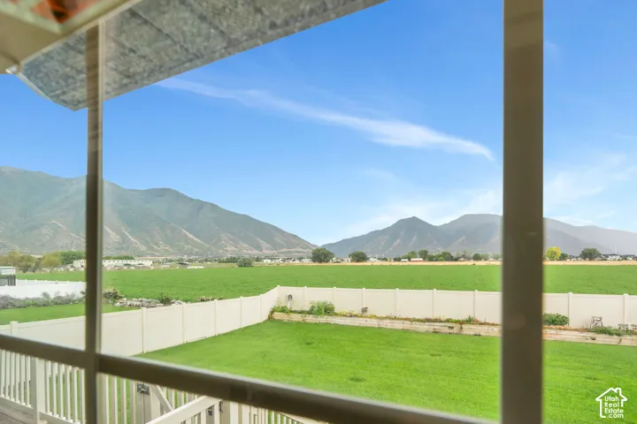 Expansive backyard featuring a green lawn, white fencing, and distant mountain scenery