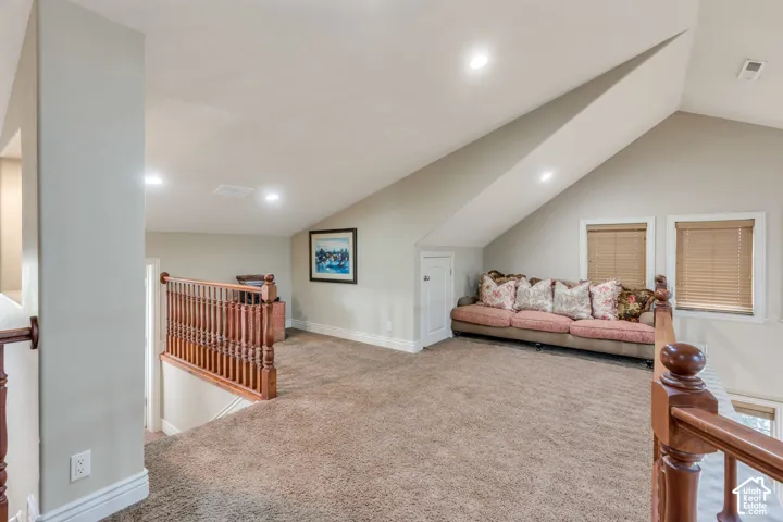Carpeted loft area featuring wood railings, recessed lighting, and two windows with blinds