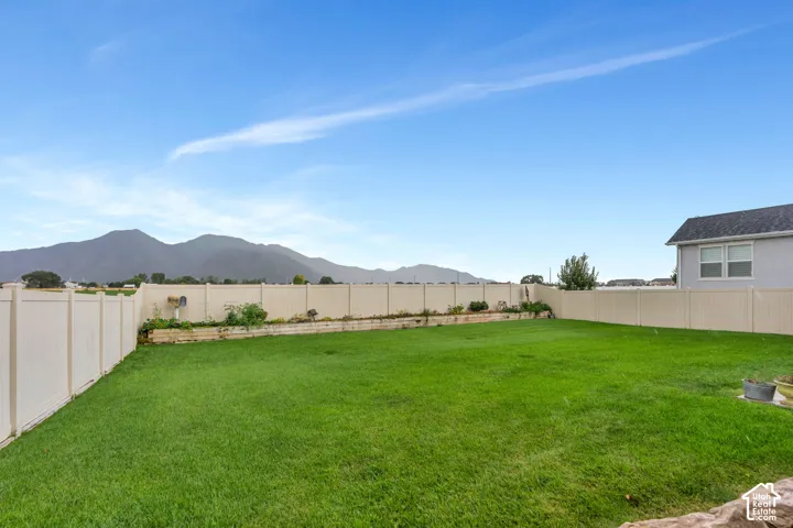 Expansive lawn with a perimeter fence, raised planting beds, and a distant mountain backdrop