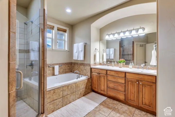 Dual vanity with light wood cabinetry, stone-finish countertop, and full-width mirror