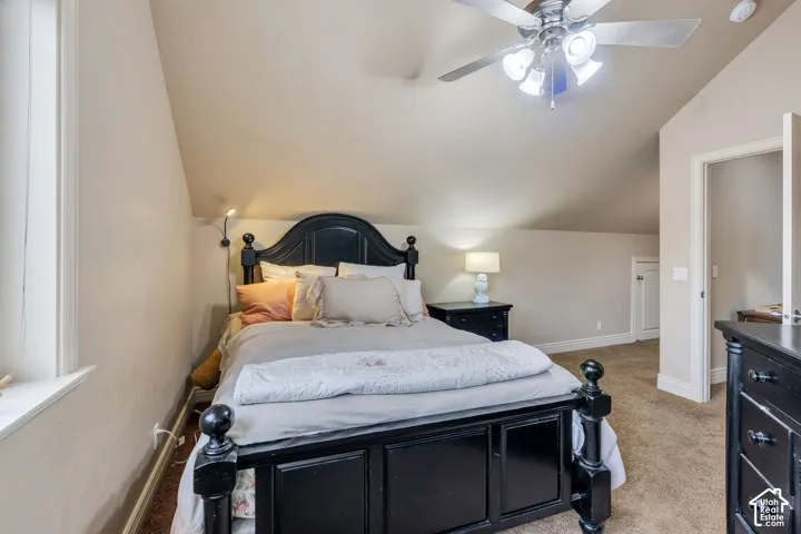 Carpeted flooring, vaulted ceiling, white trim, and a ceiling fan with integrated lighting