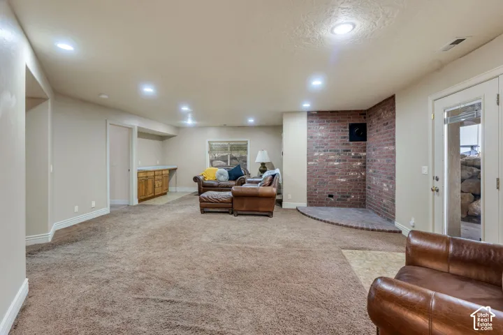 Spacious room featuring recessed lighting, a built-in wet bar with wood cabinetry, a brick accent wall, and a glass-paned exterior door