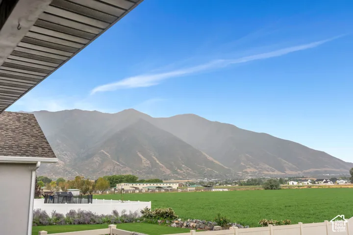 Spectacular mountain-backdrop property featuring expansive manicured grounds with vibrant green lawn, mature landscaping, and flowering garden beds