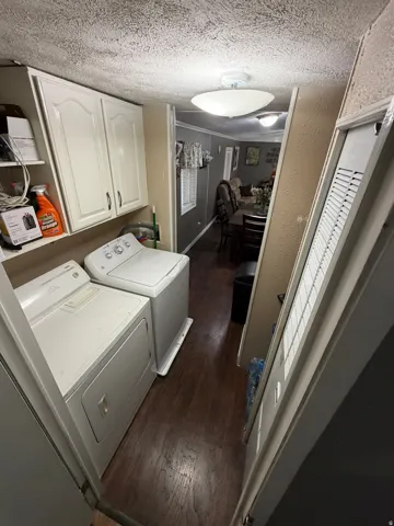 Laundry area with wood-finish flooring, white cabinetry, and overhead lighting