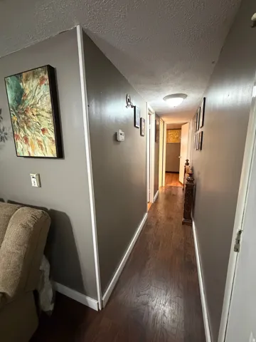 Hallway with wood-finish flooring, neutral wall color, and white trim