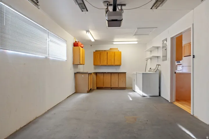 Concrete flooring, wall-mounted cabinetry, built-in shelving, overhead lighting, and two windows with blinds