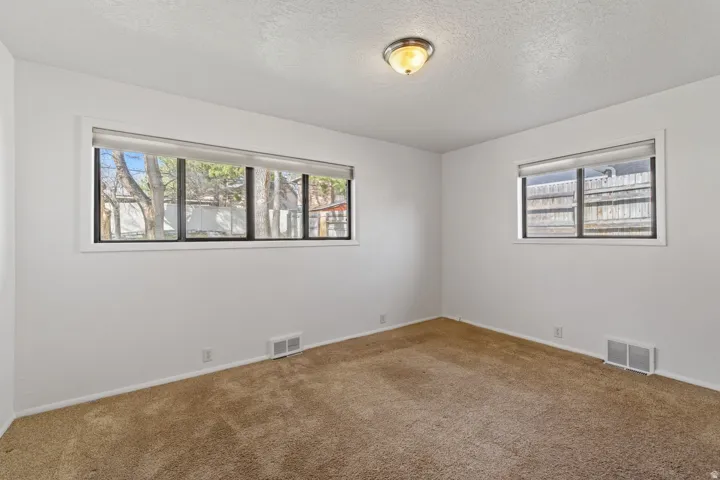 Neutral wall finishes with a textured ceiling, carpeted flooring, and a flush-mount light fixture