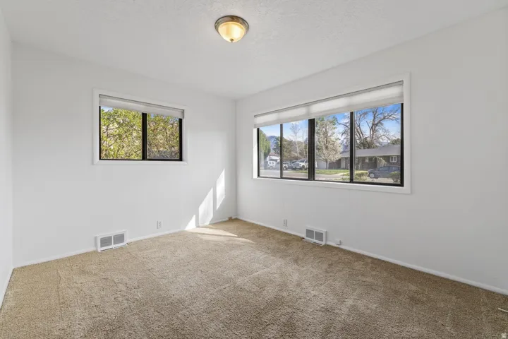 Neutral wall color with large windows and carpeted flooring