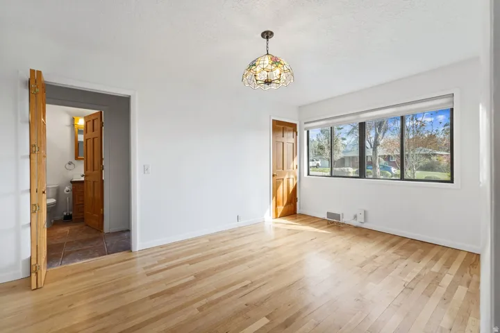Wood-finish flooring, a multi-pane window, and a decorative ceiling light fixture