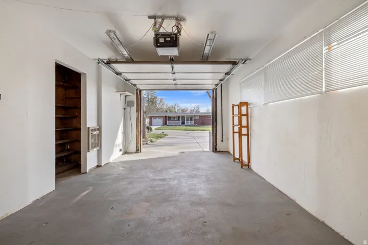 Concrete floor garage with built-in shelving, overhead lighting, and white walls
