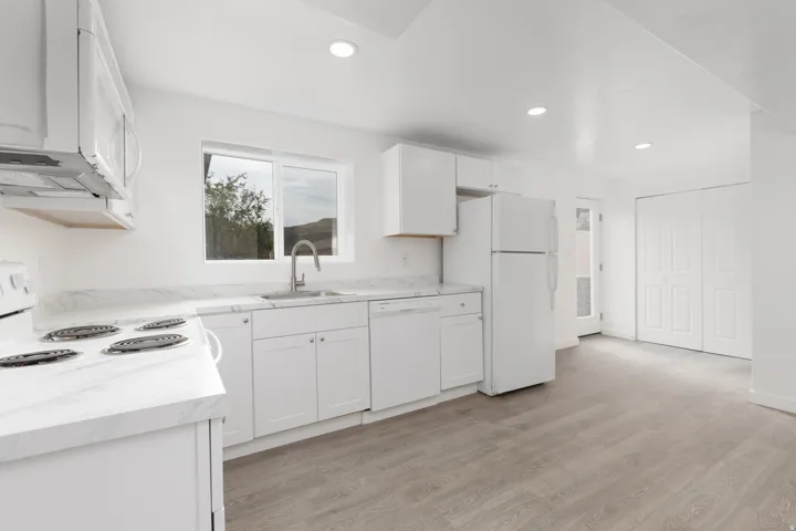 Kitchen featuring white cabinetry,  laminate countertops, stainless steel sink, and wood-finish flooring (Basement)