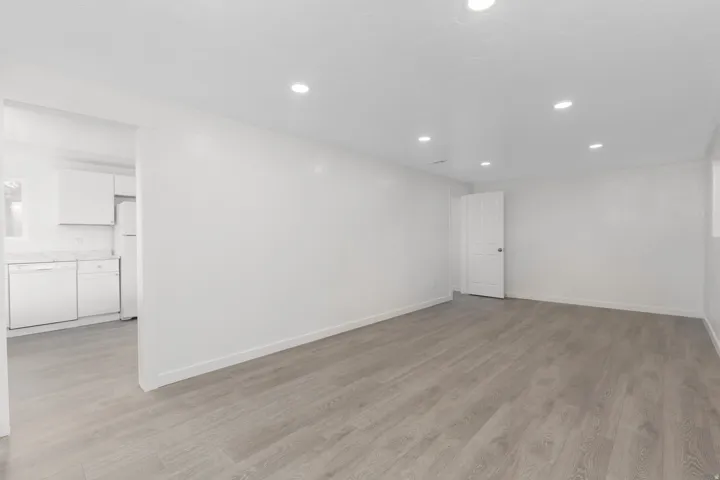 Open-concept living area with recessed lighting, wood-finish flooring, and white wall finishes